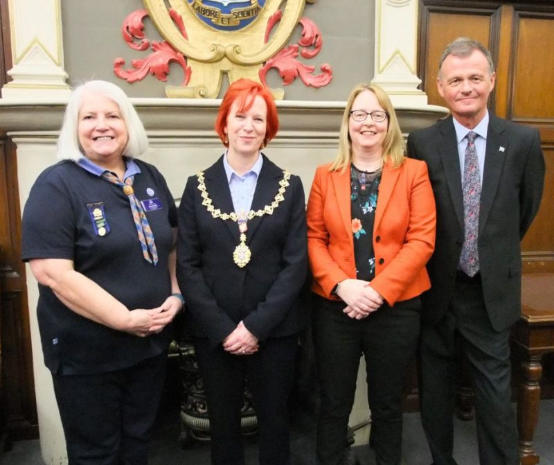 County Commissioner Lorna Hamilton with West Dunbartonshire Provost Karen Murray Conaghan, MSP Marie McNair and East Dunbartonshire councillor Jim Gibbons all stand side by side in front of a fireplace with the Clydebank coat of arms above the fireplace. They are all smiling