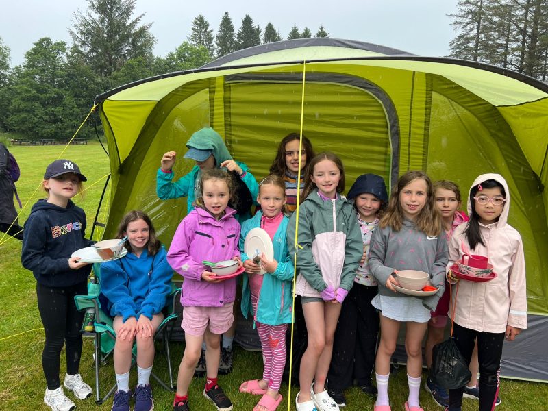 1st Bearsden Brownies outside their tent, holding their crockery and cutlery, ready for mealtime